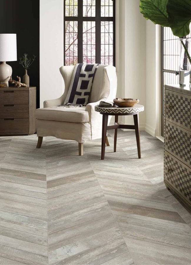 wood look tile flooring in an elegant living room with large windows and a white chair
